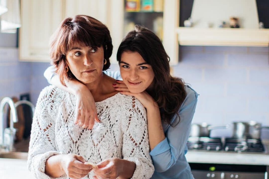 A woman and a girl share a warm moment in a cozy kitchen, highlighting the joy of baking and family connections